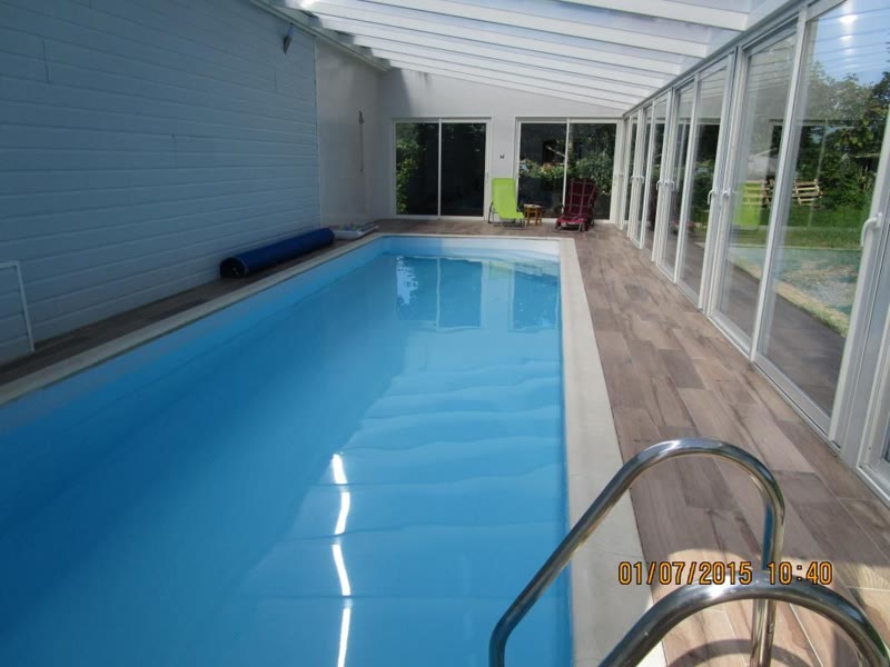 La piscine intérieure chauffée, sous une véranda vitrée